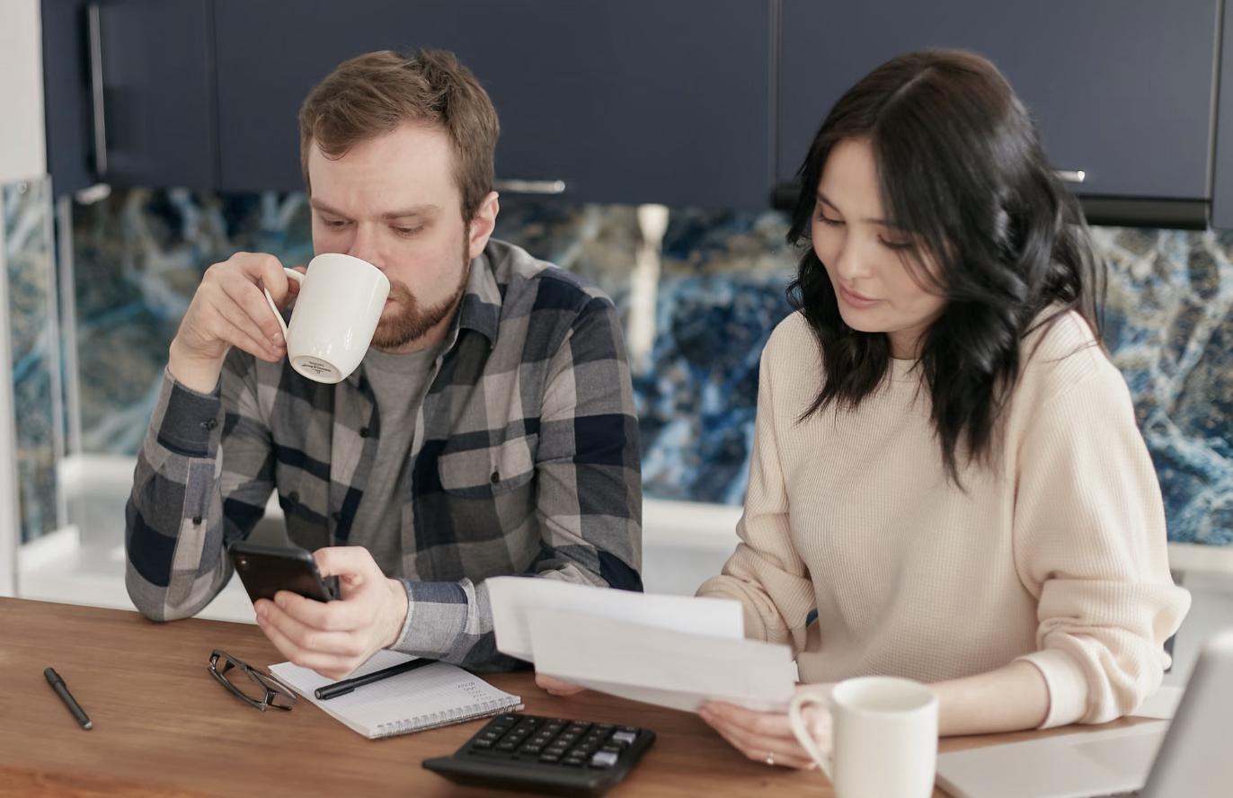 Couple qui révise ses factures et son budget familial à la maison avec une calculatrice
