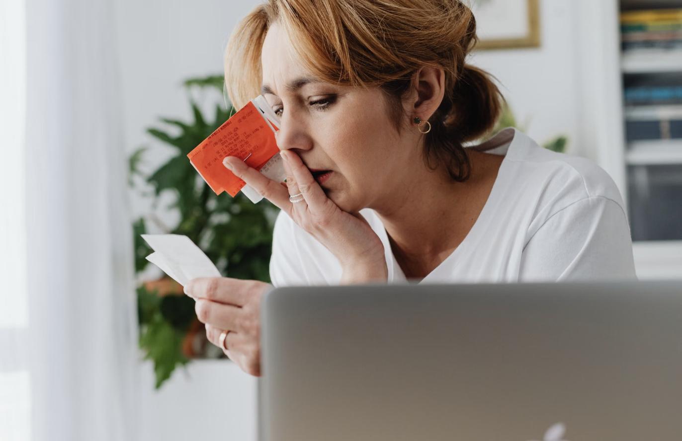 Femme qui examine ses factures et ses paiements minimums devant son ordinateur portable