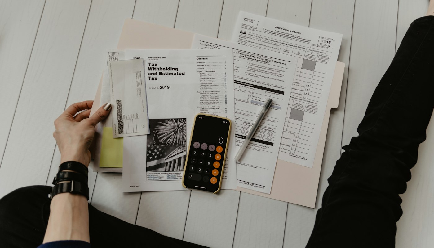 Person reviewing bills with a calculator and phone to rebuild a budget after reduced income